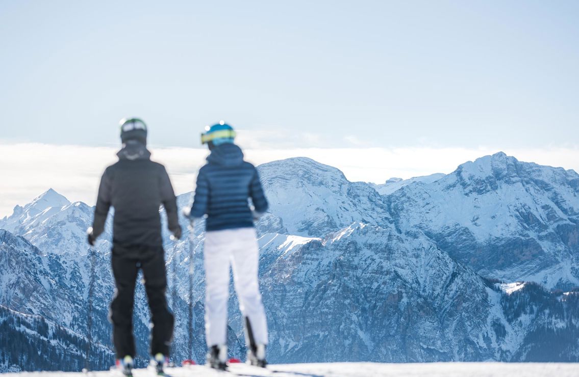 Zwei Skifahrer genießen den Ausblick beim Skifahren